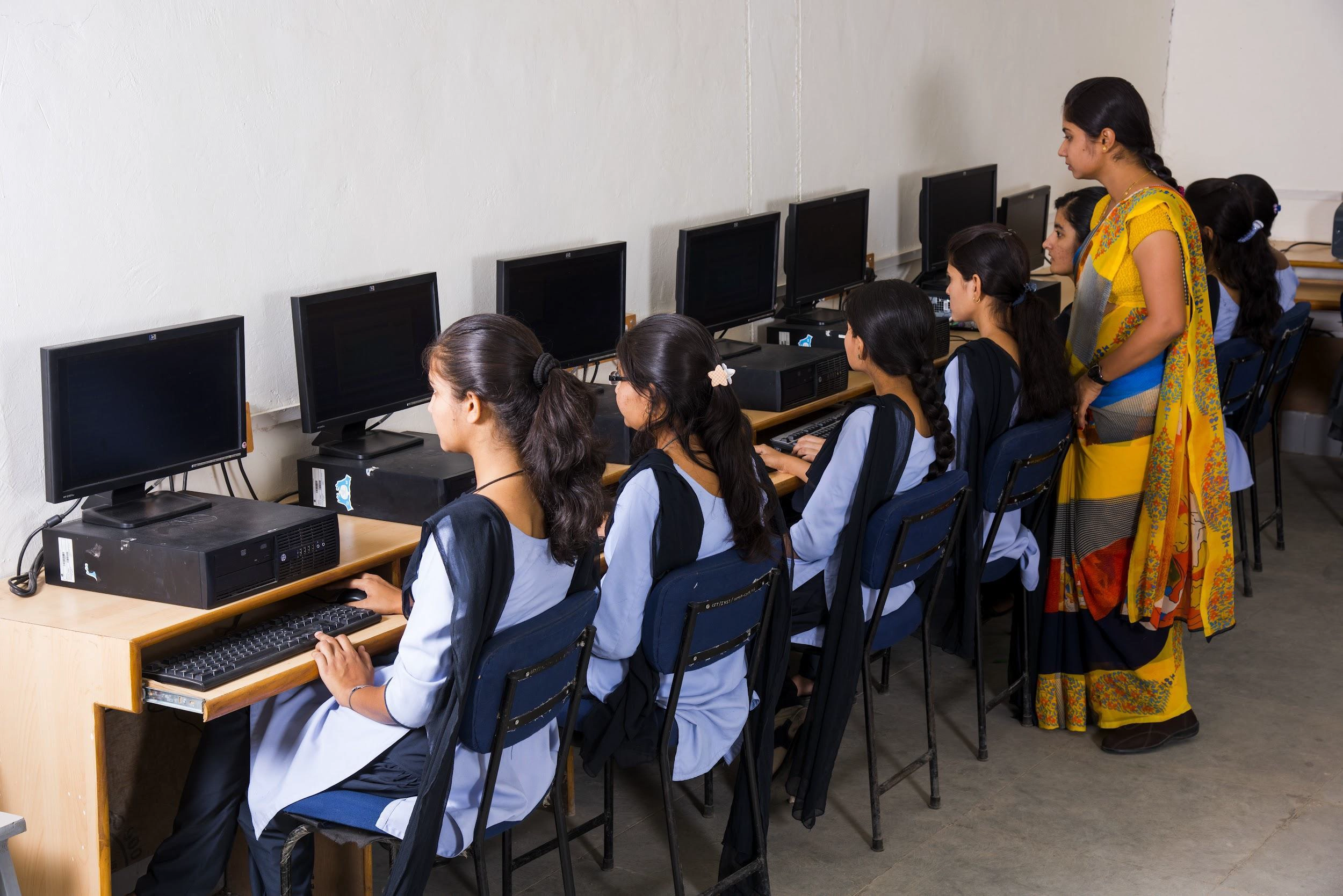 Students using computers in a classroom with a teacher